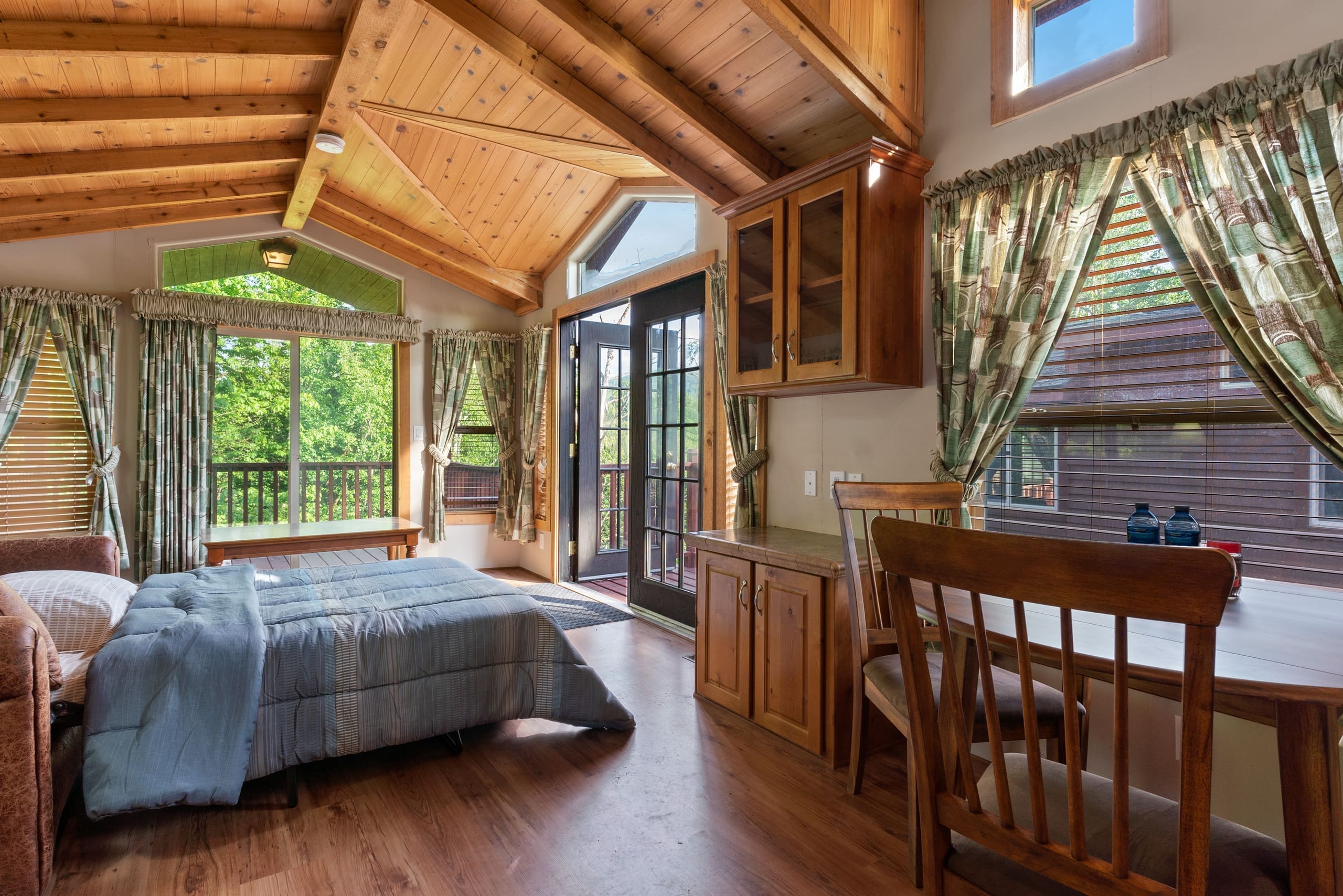 Deluxe cabin interior with vaulted cedar ceiling, bed, and dining table