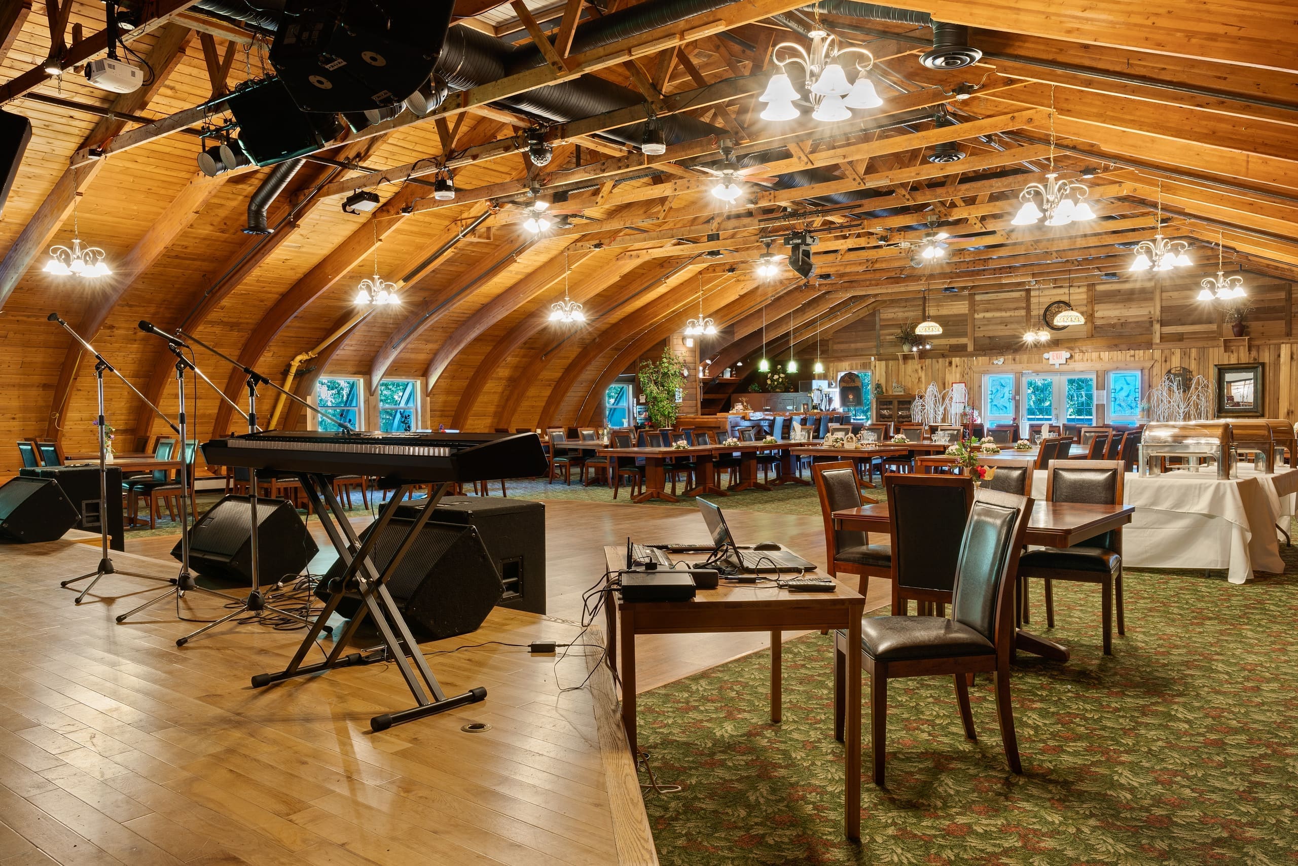 Lodge event hall with stage, microphones, and dining tables