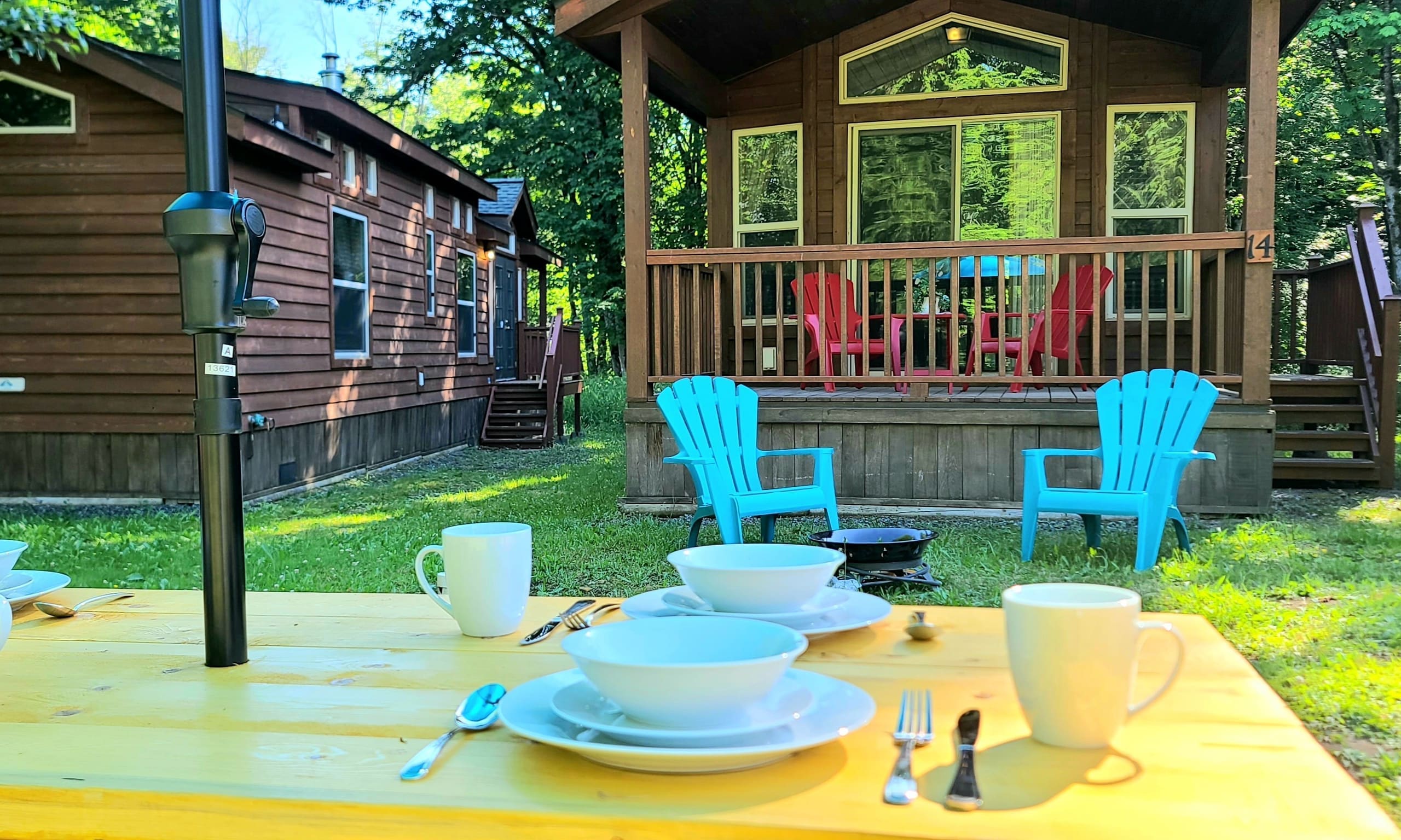 Picnic table with a blue umbrella and charcoal grill on the resort lawn