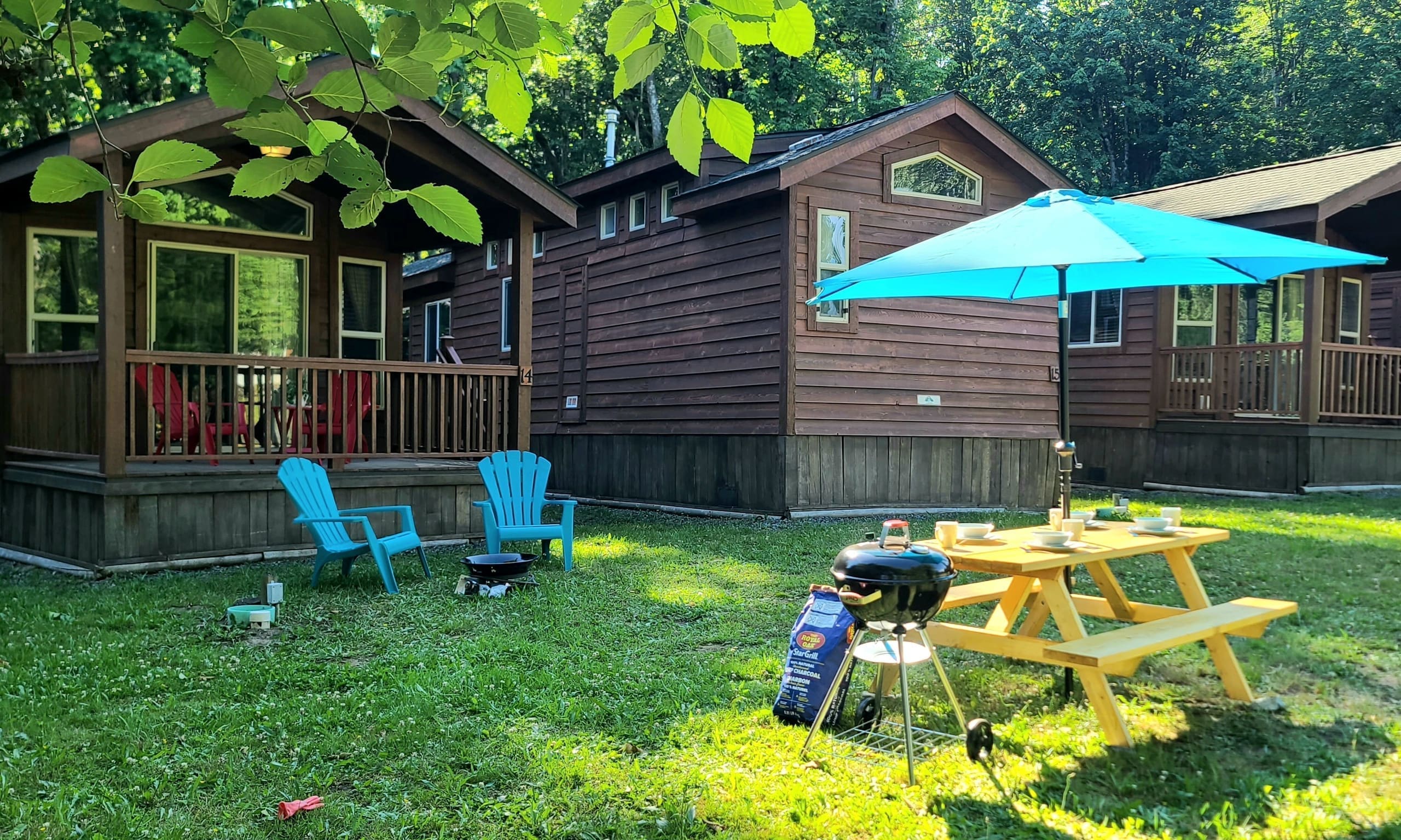 Picnic table set with mugs and bowls under a turquoise umbrella