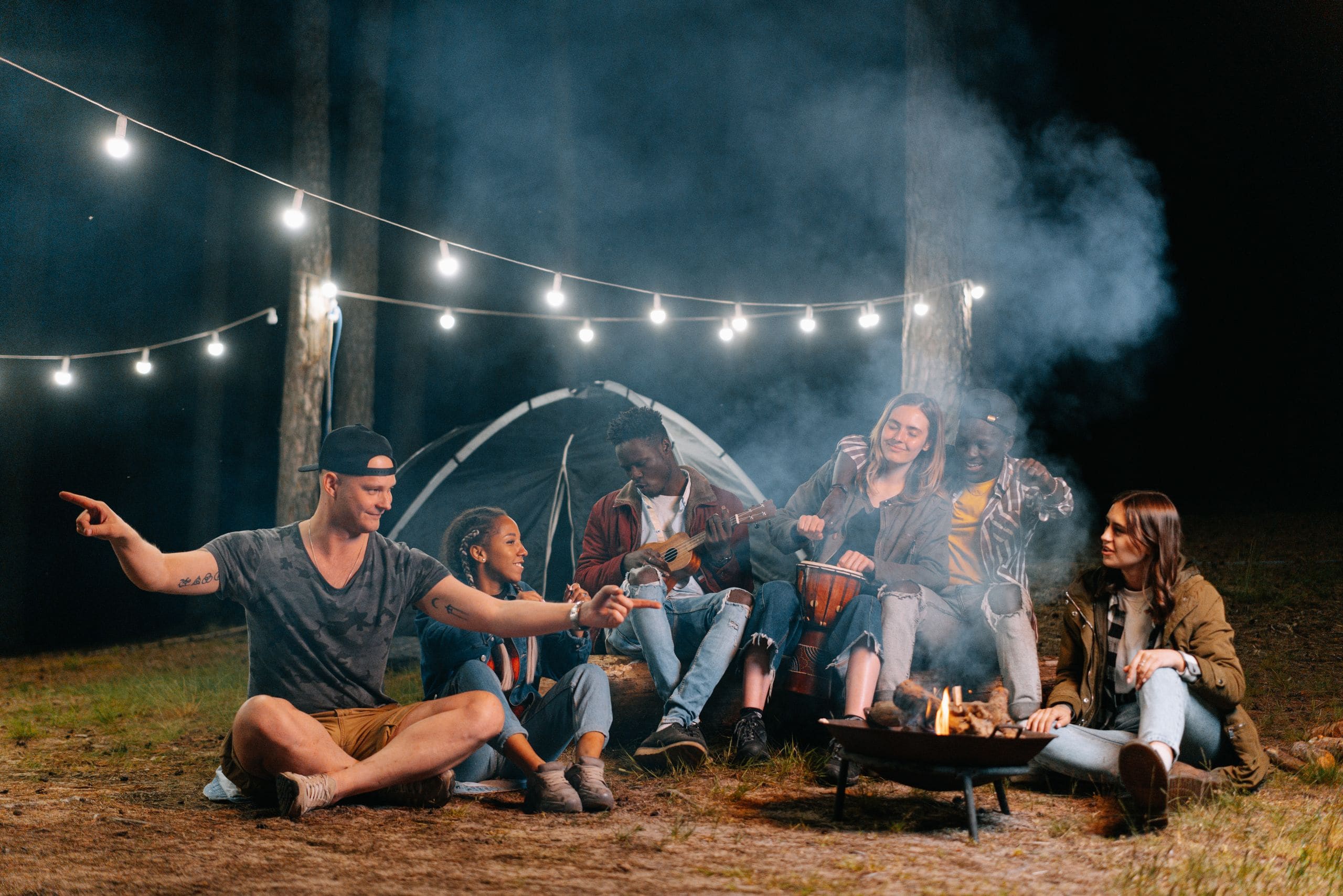 Friends gathered and laughing around a glamping fire pit under a starlit sky